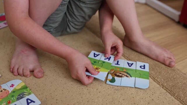 Close up shot. Hands of a child putting together letter puzzles. A  boy with Down syndrome. Family time, preschool preparations. Board games. Words, letters. 