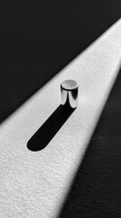 Shiny metallic object casting a long shadow on textured surface in stark lighting