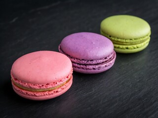 Pink purple and green macarons on black background