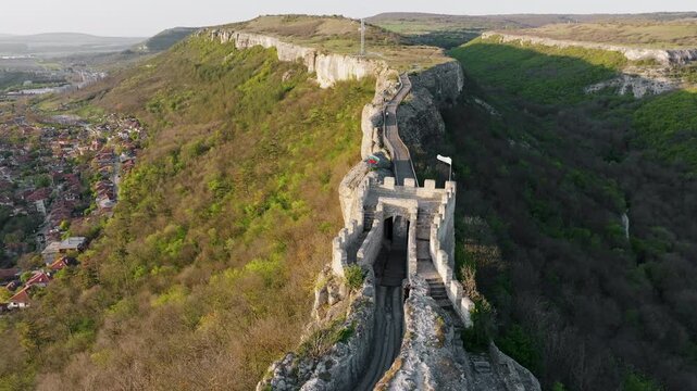 Wooden bridge to medieval Ovech Fortress ruins in Provadia Bulgaria, summer drone shot over green mountain, historic Balkan destination, scenic landscape for cultural historical stock themes