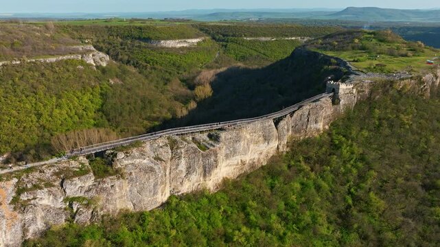 Wooden bridge to medieval Ovech Fortress ruins in Provadia Bulgaria, summer drone shot over green mountain, historic Balkan destination, scenic landscape for cultural historical stock themes