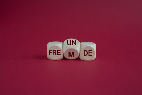 Turned the dice and changes the German word Fremde strangers into Freunde friends. Symbolizing that strangers can become friends. Beautiful red background.