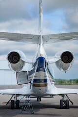 Rear view of a business jet on the apron, displaying both jet engines, landing gear, and open cargo...