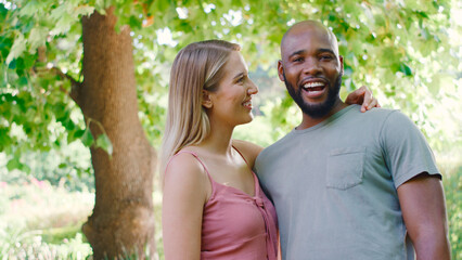 Portrait Of Loving Multi-Racial Couple Standing Outdoors In Garden Park Or Countryside