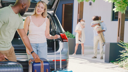 Grandparents Greeting Grandchildren As Family Unpack Car On Family Holiday