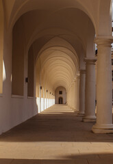 Fototapeta premium A long, shaded corridor with white arches and columns, offering a minimalist and architectural perspective.