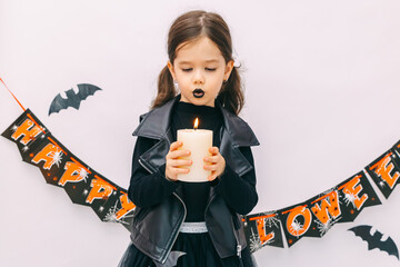 Little adorable cute Caucasian girl with curly hair and black lips blowing candle with fun and...