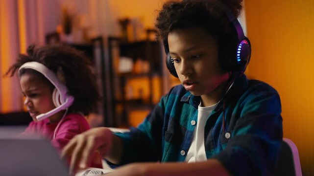Little boy and girl losing in online multiplayer game, playing on their laptops