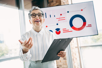 Confident businesswoman presenting data analysis in modern office with charts