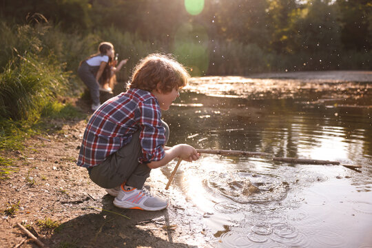 Cute little boy and other children playing by lake in nature, selective focus