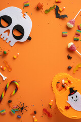 Orange vertical backdrop with Halloween elements, including candies, skull mask, and festive...