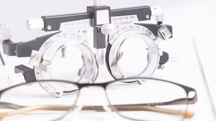 A pair of eyeglasses sits on a table next to a device that measures the distance between the eyes