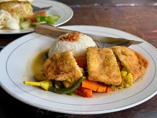 A plate of chicken katsu with vegetables curry and white rice