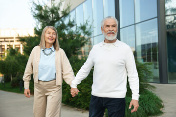 Lovely senior couple walking together near building outdoors