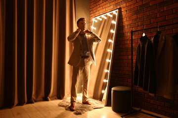 Handsome man getting ready near mirror indoors