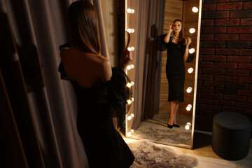 Woman with comb getting ready near mirror indoors