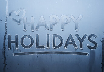 Happy holidays message written in condensation on a window