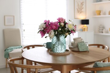 Dining table with beautiful flowers and dishware in room. Interior design