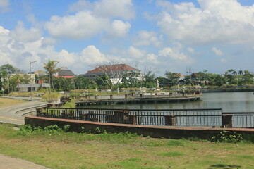 view of the clean Sanur dam with green plants growing on the edge of the lake in clear weather with a blue sky visible