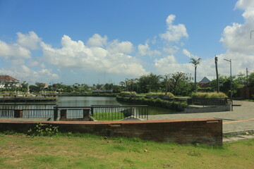 view of the clean Sanur dam with green plants growing on the edge of the lake in clear weather with a blue sky visible