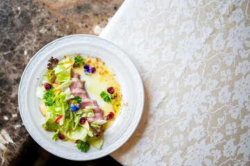 Gourmet salad with cooked meat slices, fresh greens, apple, cranberries, parsley, and edible...