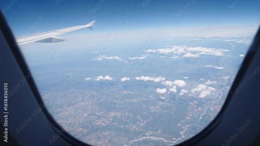 Poster aerial view from airplane window showing clouds and land during day flight