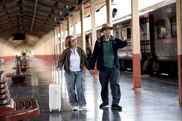 Fototapeta premium Asian adult travelers holding hands exploring classic train station platform ready for exciting holiday adventure journey destination discovery