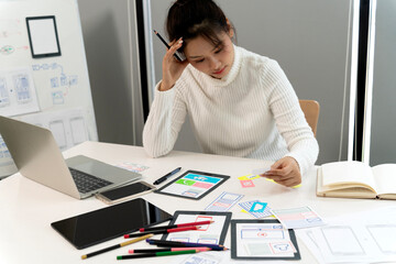 Asian young adult woman designing user interface experience for mobile app development creative...