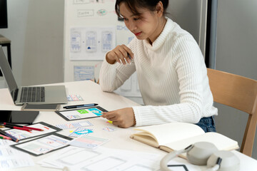 Asian young adult woman digital designer developing mobile application user interface user...