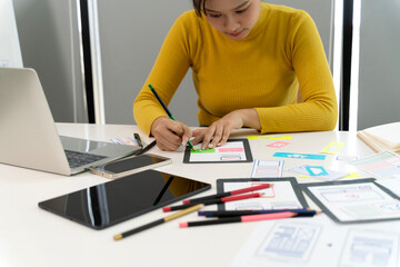 Asian adult woman UX UI designer developing app website wireframes digital product innovation focused on modern office environment layout design technology