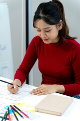 Asian woman designer creates user interface website application design sketches prototyping development office workspace