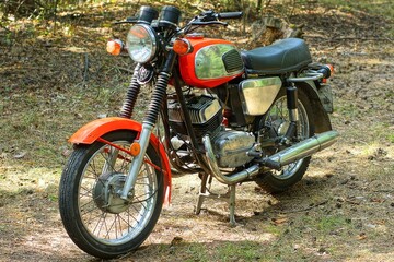 one old red chrome two wheel industrial retro heavy with black soft saddle iron industrial with round headlight motorcycle standing on ground day