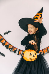 Happy child girl in witch costume has fun and dancing on halloween party. lantern jack, happy...