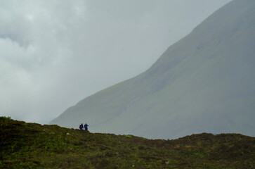 Two trekkers brave rainy spring weather on a trail in the Red Cullins on the Isles of Skye,...