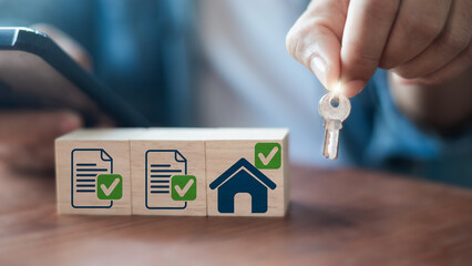 Hand holding house key with document checklist icons, approved contract, and home loan concept....