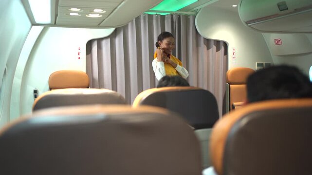 Flight attendant demonstrating the use of emergency and safety equipment to passengers onboard before takeoff.