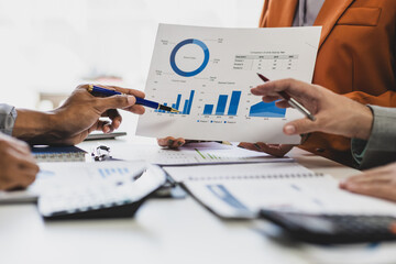 Business people analyzing financial chart and business data on office desk. Business colleagues reviewing financial reports and analyzing statistical charts during a meeting.