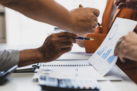 Business people analyzing financial chart and business data on office desk. Business colleagues reviewing financial reports and analyzing statistical charts during a meeting.