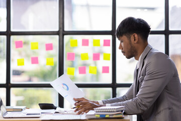 Businessman analyzing financial report with charts in office. Professional examining financial documents.