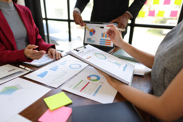Business people analyzing charts and graphs, discussing financial report  using laptop and documents during a meeting in office.