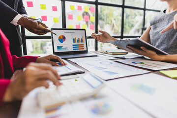 Business people analyzing financial charts and graphs on laptop and document. Business colleagues are discussing financial data displayed on a laptop and printed documents.