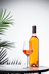 Elegant rose pink wine served in a glass beside a bottle against a minimalist backdrop for a...