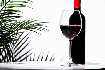 Non-alcoholic red wine in an elegant goblet beside a bottle with a stylish backdrop featuring...