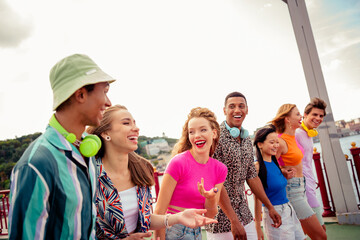 Happy group of diverse young friends enjoying summer outdoors together, bonding and laughing in casual attire, urban background