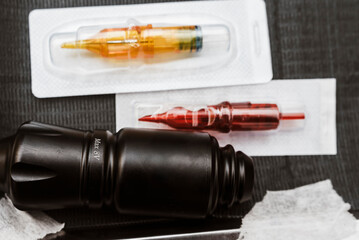 Tattoo pen machine placed beside sealed red and yellow cartridges on a sanitized surface, ready for...