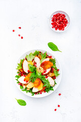 Yummy persimmon salad with grilled chicken, pomegranate, walnuts, oranges and lettuce, top view