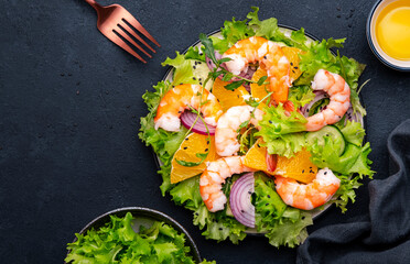 Juicy shrimp salad with orange, lettuce, red onion with olive oil and juice dressing, black...