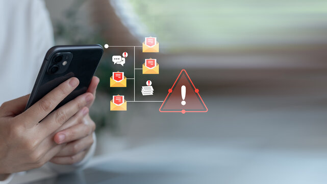 Close-up hand holding smartphone with warning icon and phishing email notification. Concept of cybersecurity threats, email scams, data breaches, and mobile fraud.