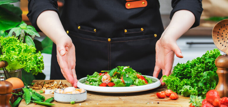 dedicated chef prepares vibrant salad with fresh greens and vegetables in a well-equipped kitchen, showcasing healthy living. - Powered by Adobe
