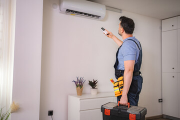 Technician testing air conditioning with remote control